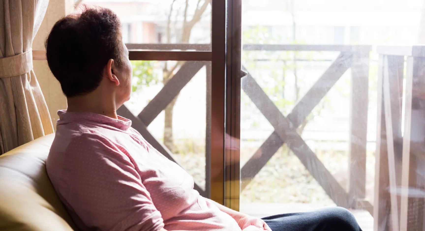 家から外を見る男性